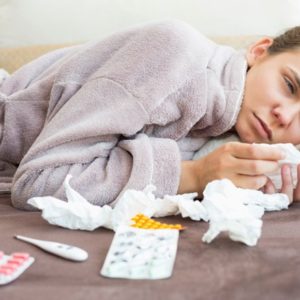 Sick woman lying in bed with medicine