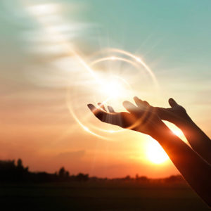 Woman's hands opened up for blessing against sunset background