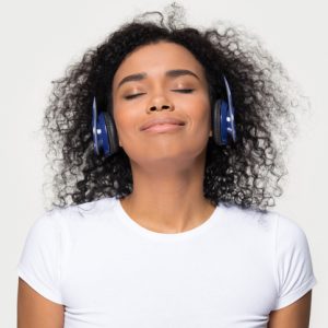 Happy, calm woman wearing headphones listening to guided meditation
