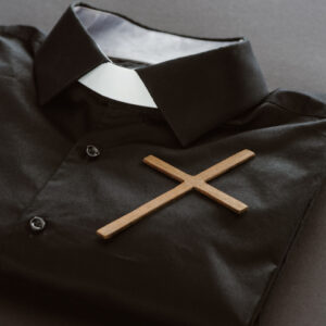 An empty priest's shirt with a cross and priest collar.