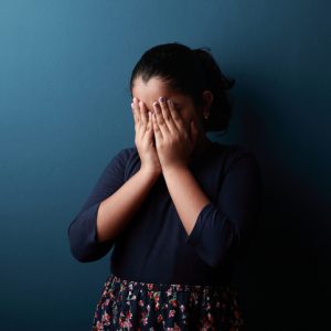 young girl covering her face in shame