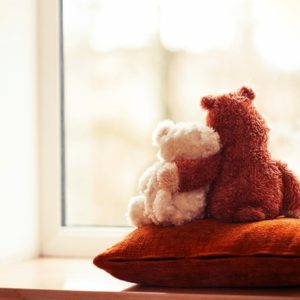 Two teddy bears embracing on pillow