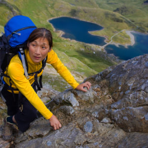 Woman climbing rocky mountainside