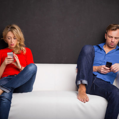 Couple sitting on couch with phones