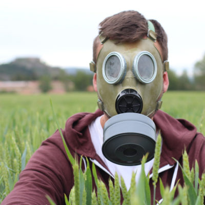 Man wearing breathing mask in wheat field.