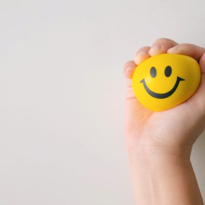 The positivity plague, hand squeezing smiley face stress ball