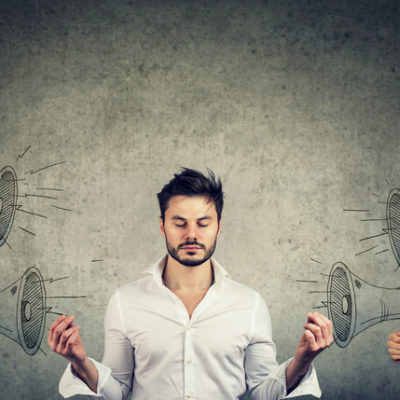 meditating young businessman paying no attention to crowd