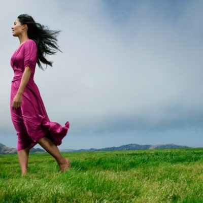 Woman barefoot in field with overcast sky