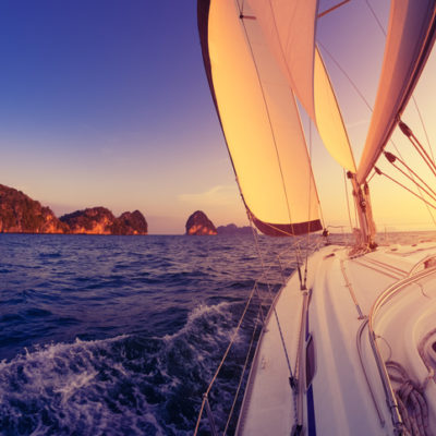 A sailboat sails toward a rocky island