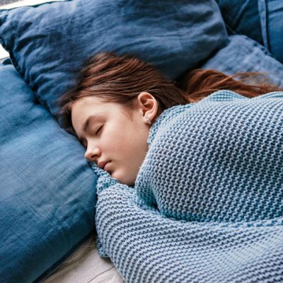 Girl with the winter blues in her bed with blue pillows and bedsheets