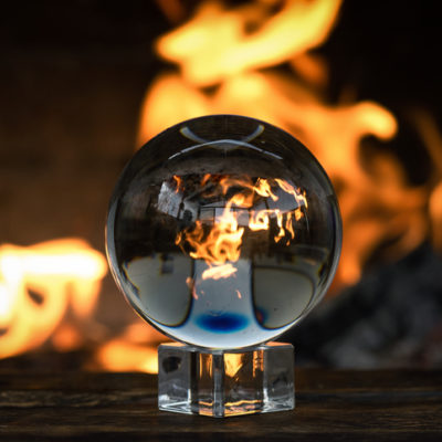 Crystal ball on a magic table on a burning fire flame background.