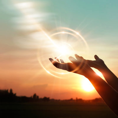 Woman's hands opened up for blessing against sunset background