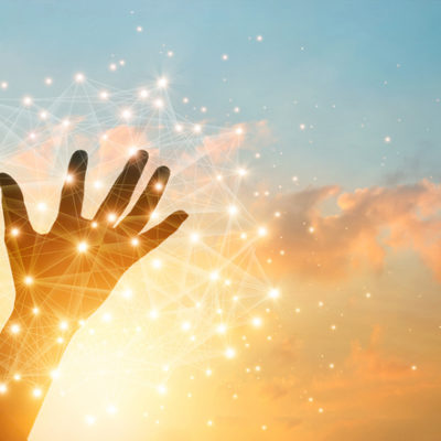 Hand touching network of light on a background of a sunset.