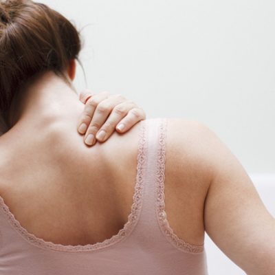 Woman massaging shoulder in need of yoga for tight shoulders