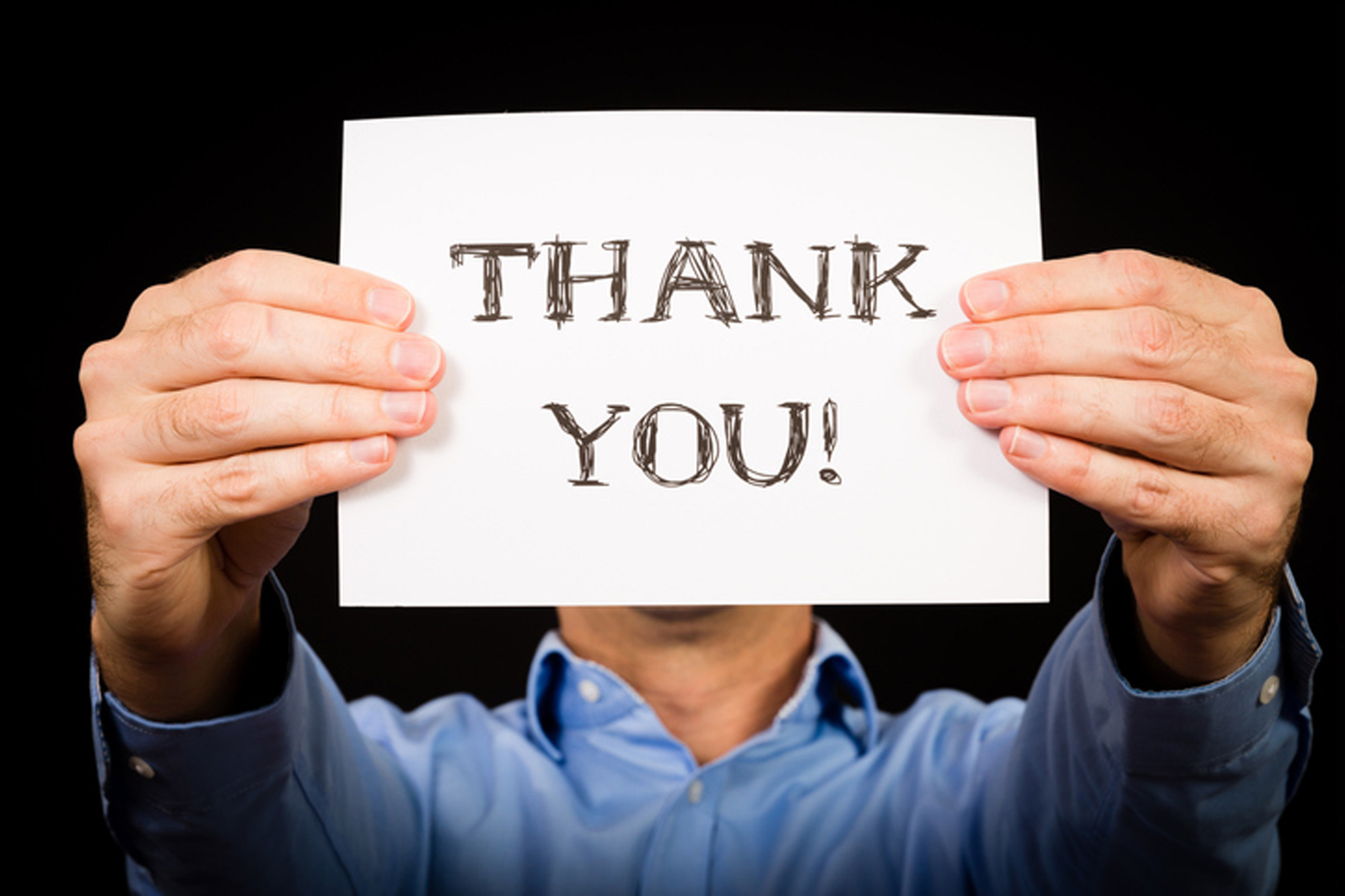 A person holding a handwritten thank you sign