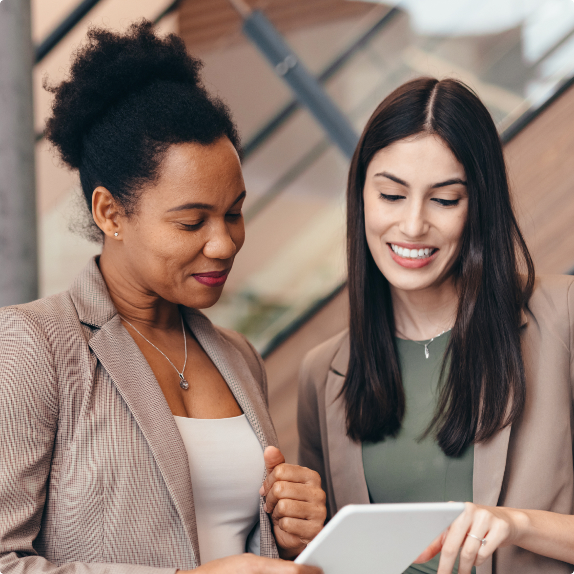 Two lady colleagues smiling and working at office
