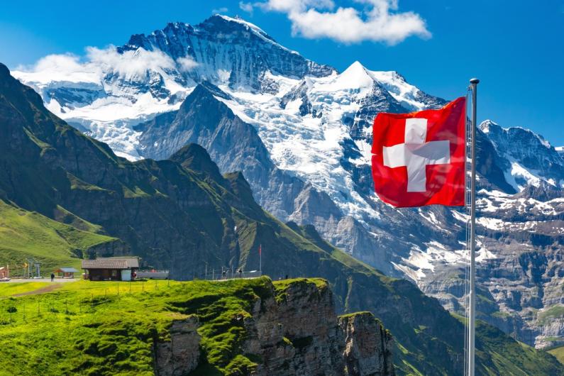 A view of the Swiss flag and a beautiful landscape in the background.