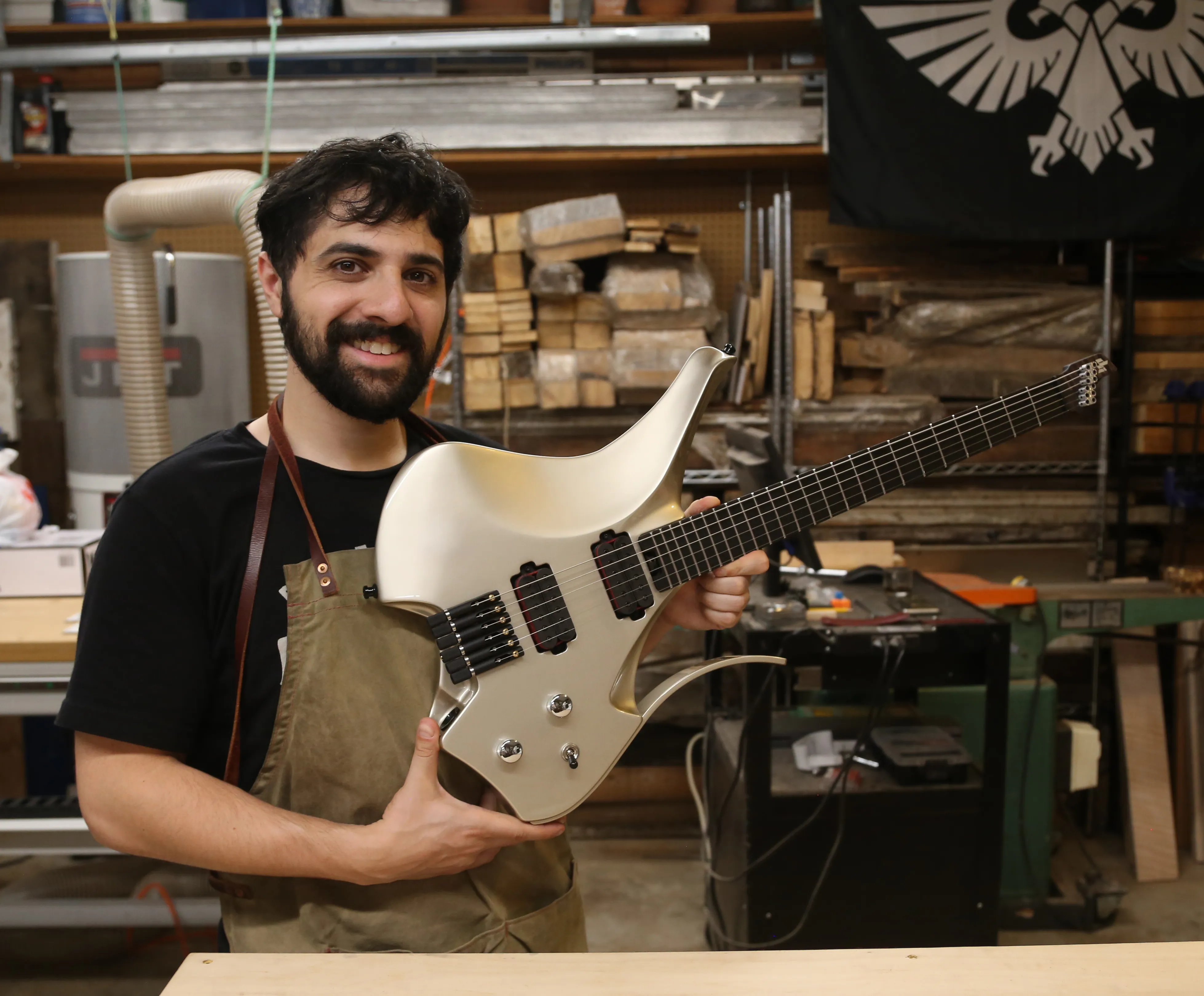 Dean Gordon holding a completed custom guitar in his workshop