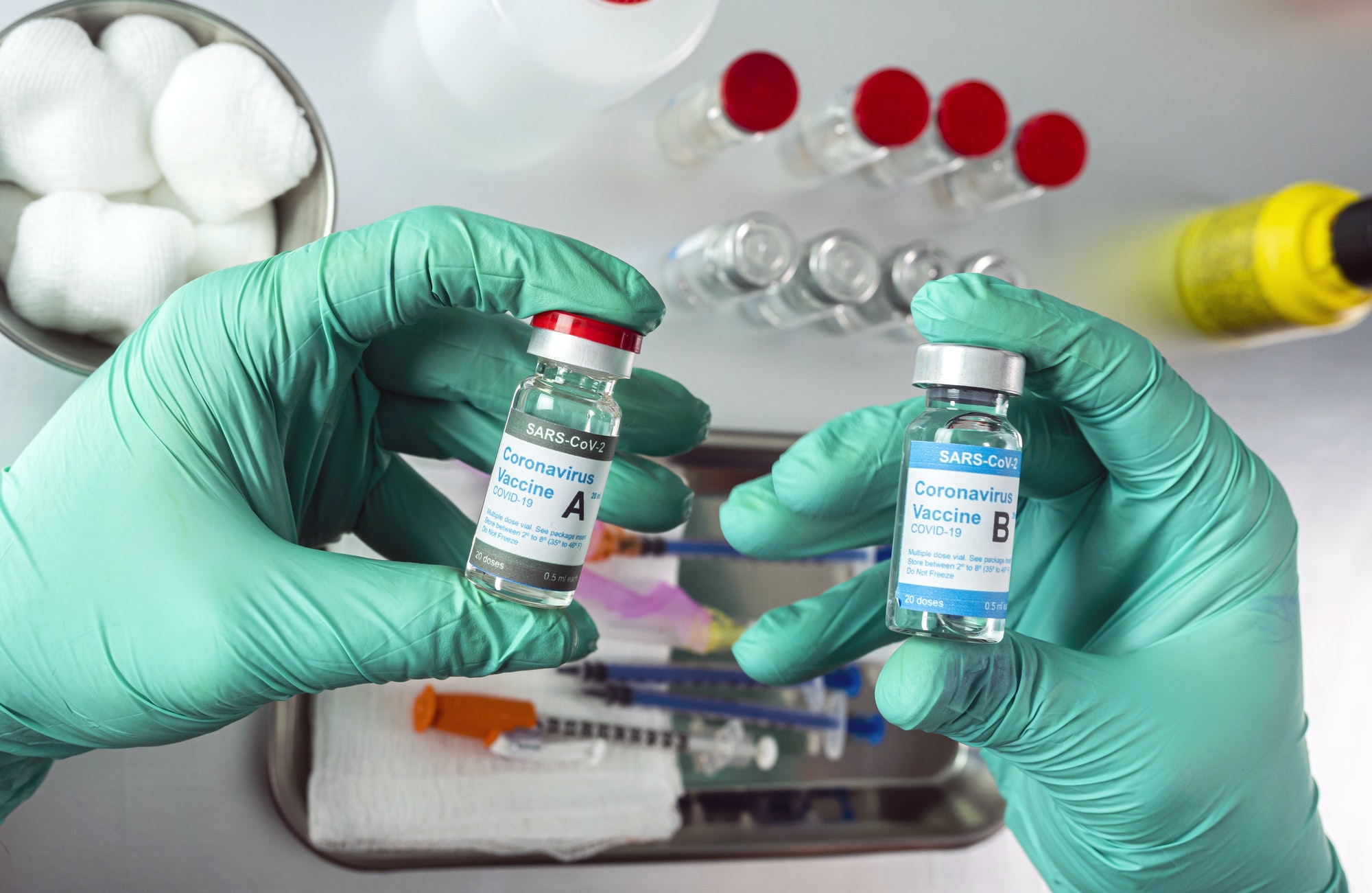 Nurse holds two covid-19 vaccines from different laboratories, conceptual image