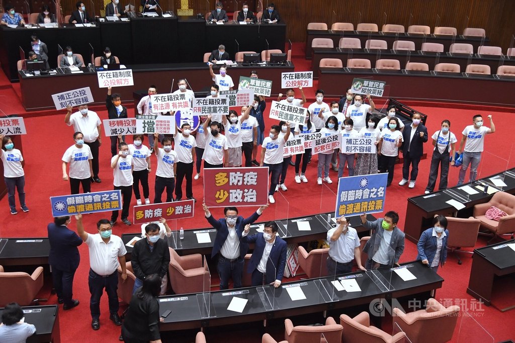 國民黨立法院黨團建請召開臨時會審議公投法修正草案，納不在籍投票。立法院7日召開全院委員談話會處理，經表決後，因民進黨團反對，國民黨團提案未通過。圖為表決時國民黨立委（後排白衣）與民進黨立委（前排）互相以標語表達立場。中央社記者王飛華攝 110年7月7日