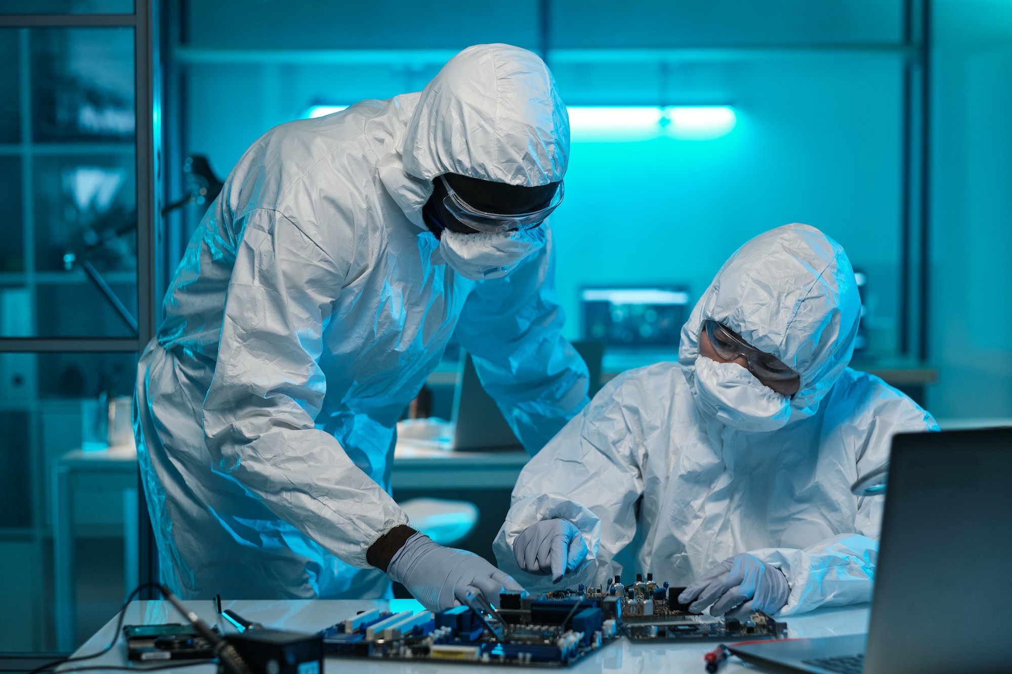 Two contemporary lab workers in protective coveralls