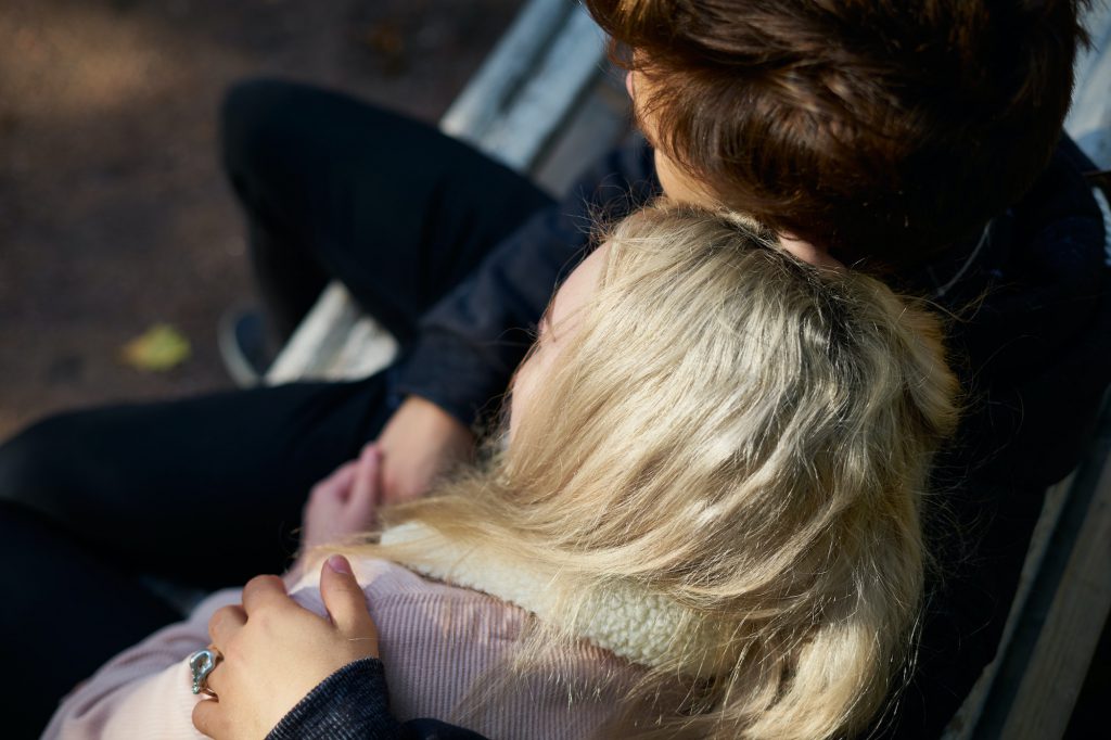 loving couple of men and women sitting on a bench, resting in the rays of the autumn sun