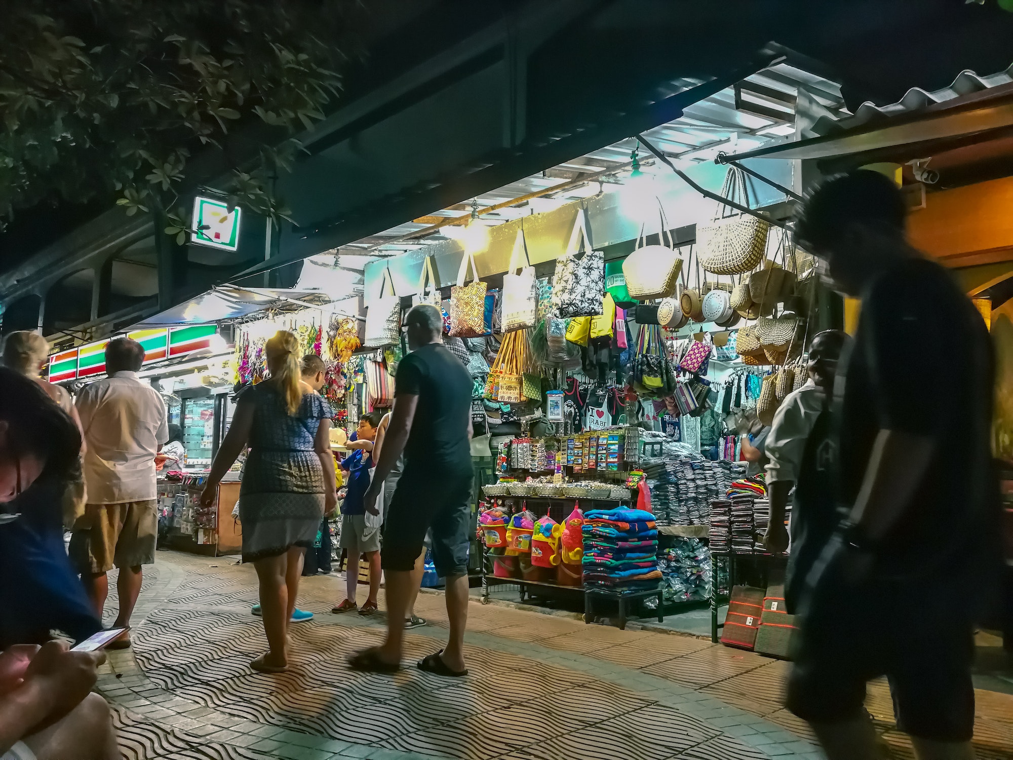 people walking near the handbag souvenir shops at night