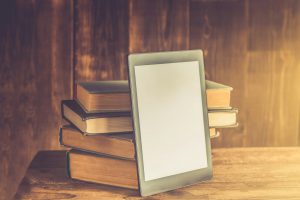 Ebook, digital tablet device, with old real books nearby