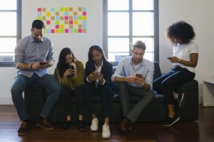 Colleagues sitting on couch using cell phones