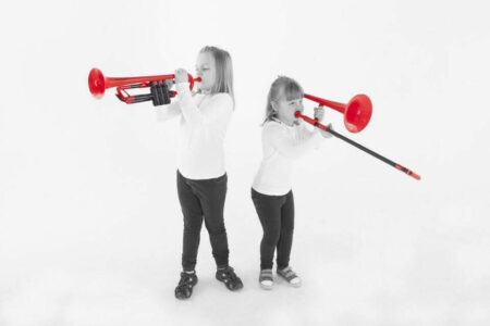 two girls in black and right stood playing red pInstruments with their backs to each other