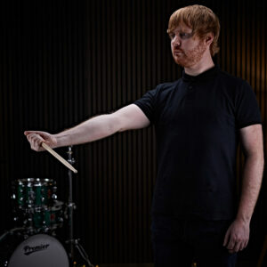 A drummer stretching his wrist with a drumstick before drumming