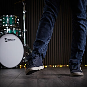 A man wearing jeans warming up his ankles before drumming