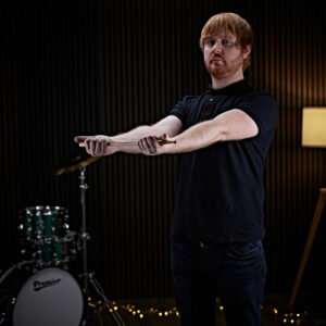 A drummer stretching his arms whilst holding a drumstick