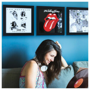 A woman smiling, looking at her records, with vinyls in the Show And Listen LP Frames in Black on a blue wall