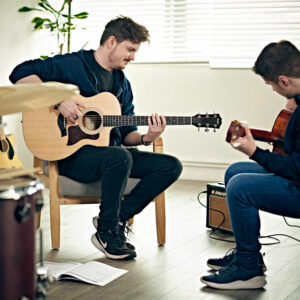 A beginner guitarist playing a Taylor acoustic guitar 