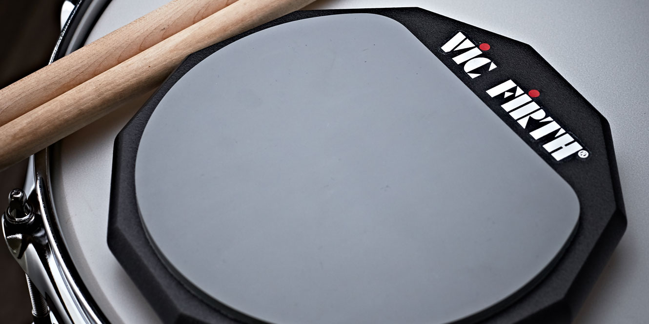 Vic Firth practice pad on a drum next to drum sticks