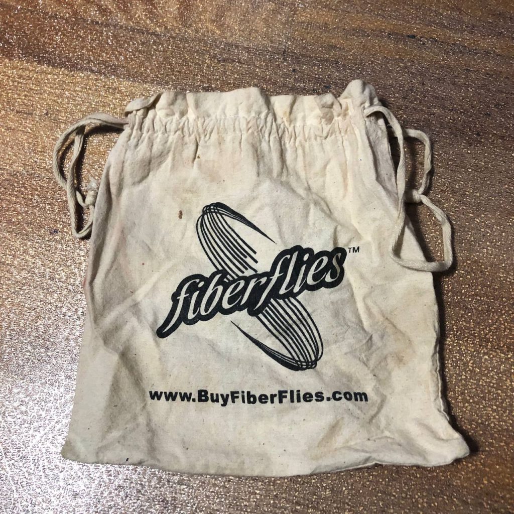 natural cotton drawstring bag with a screenprint of an illustrated swoop andof the words "fibreflies"