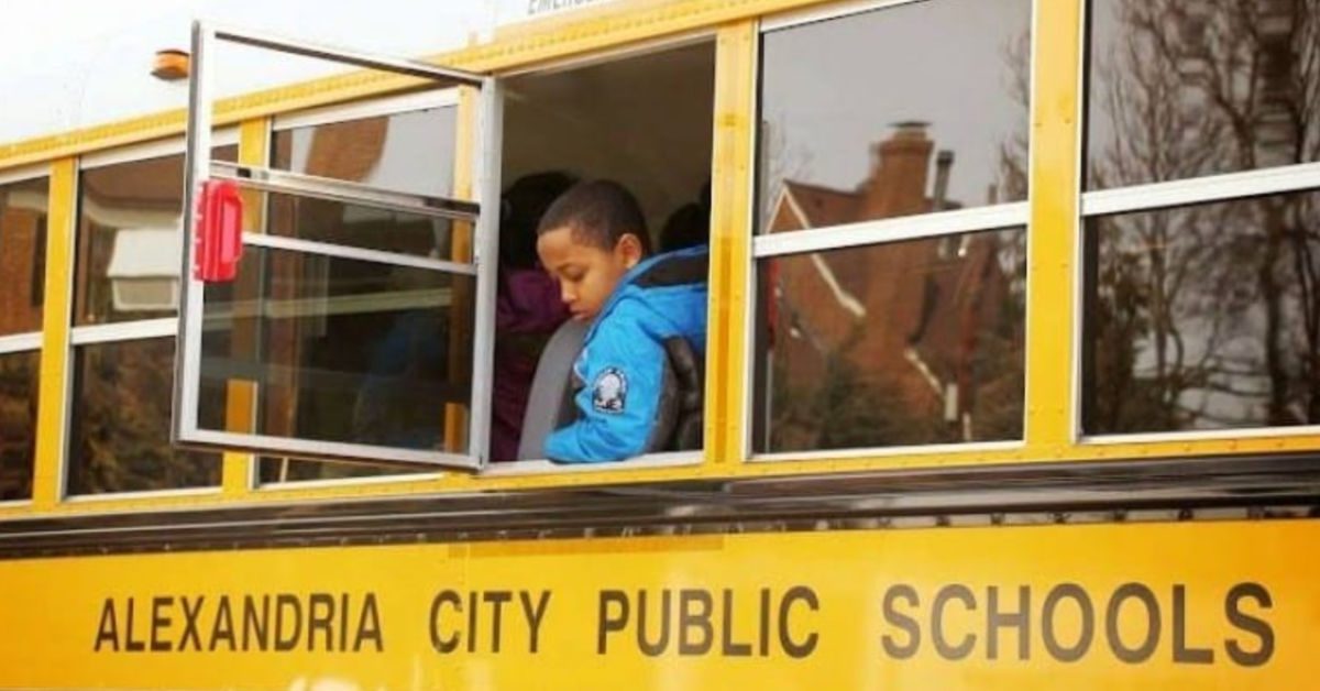 A student sits beside an open window on a yellow Alexandria City Public Schools bus.