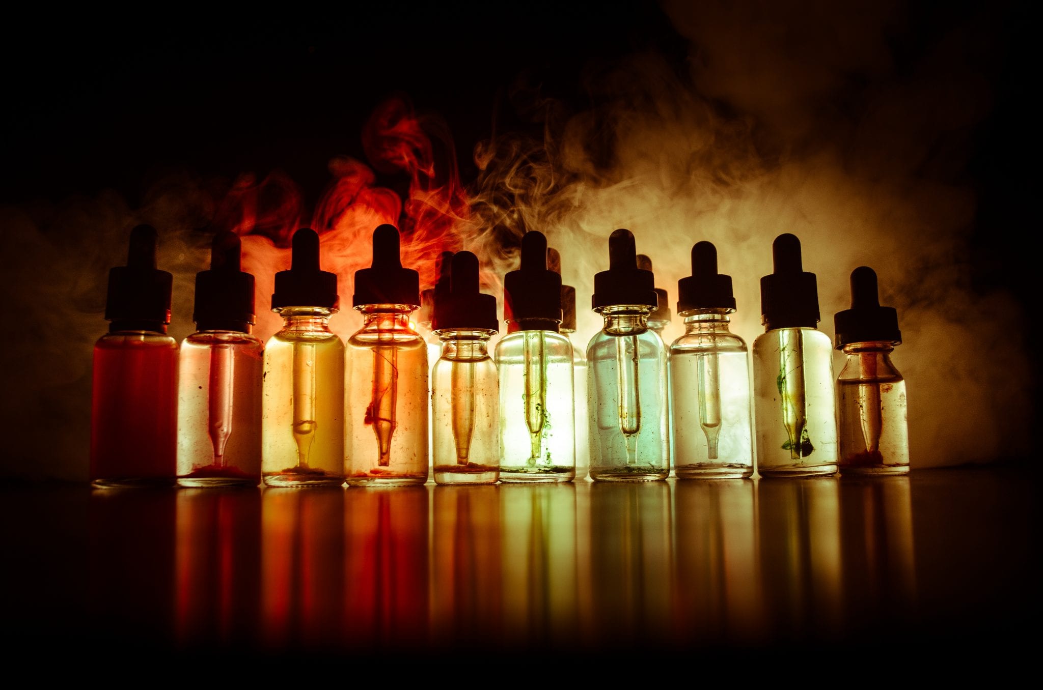 Vape concept. Smoke clouds and vape liquid bottles on dark background. Light effects. Useful as background or vape advertisement or vape background.