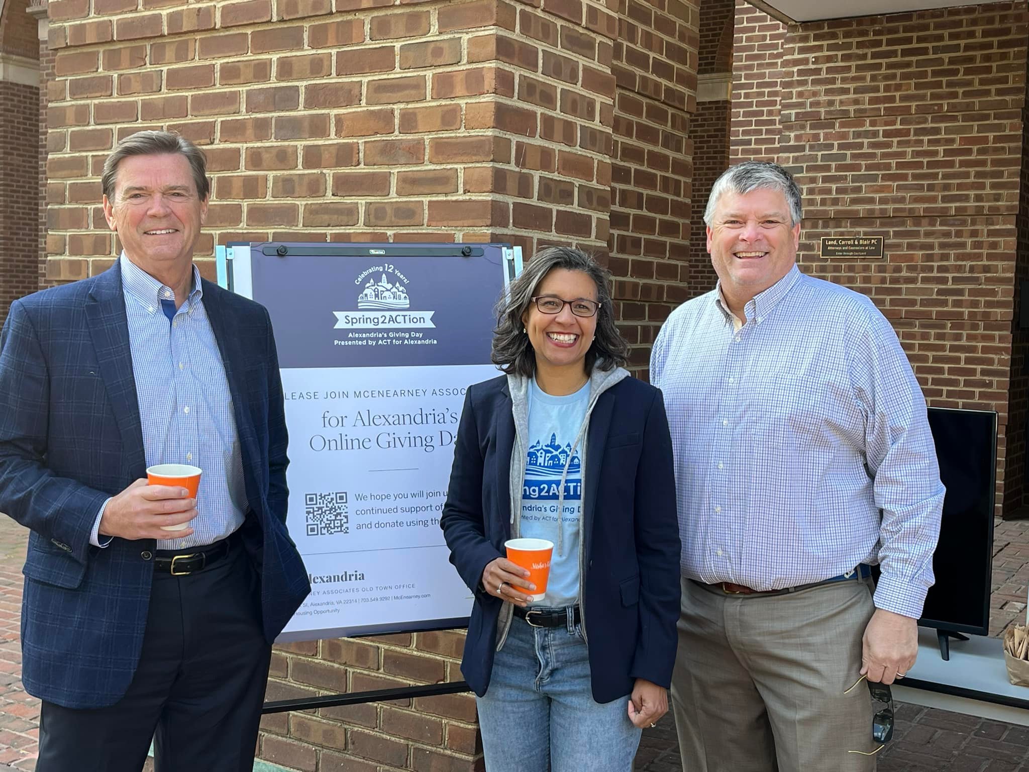 3 people in front of sign holding coffee