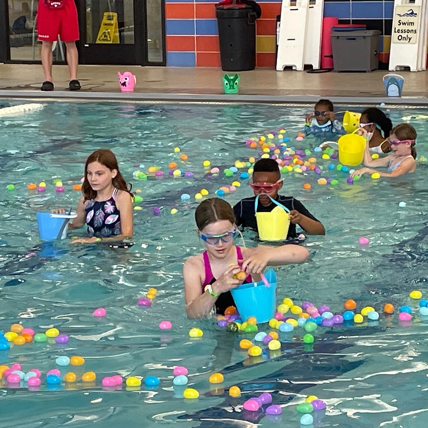 children hunt for Easter Eggs floating in an indoor pool