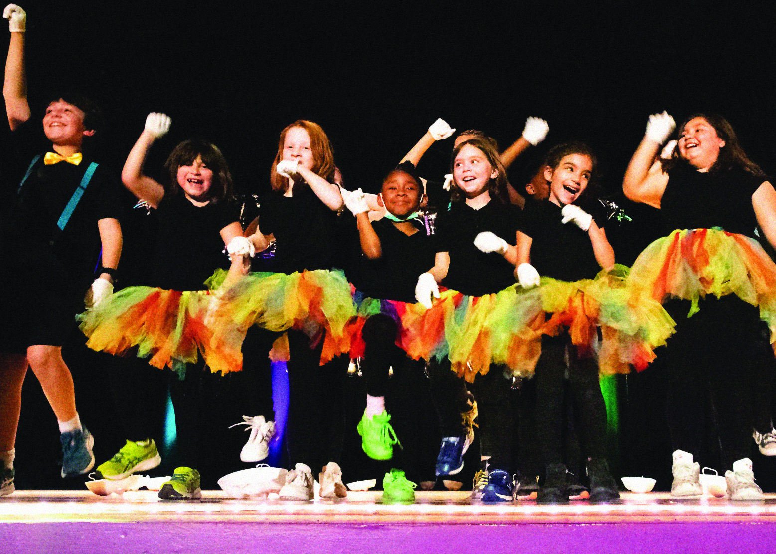 group of students in rainbow tutus dance on stage
