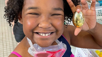 little girl smiles holding golden easter egg in her hand