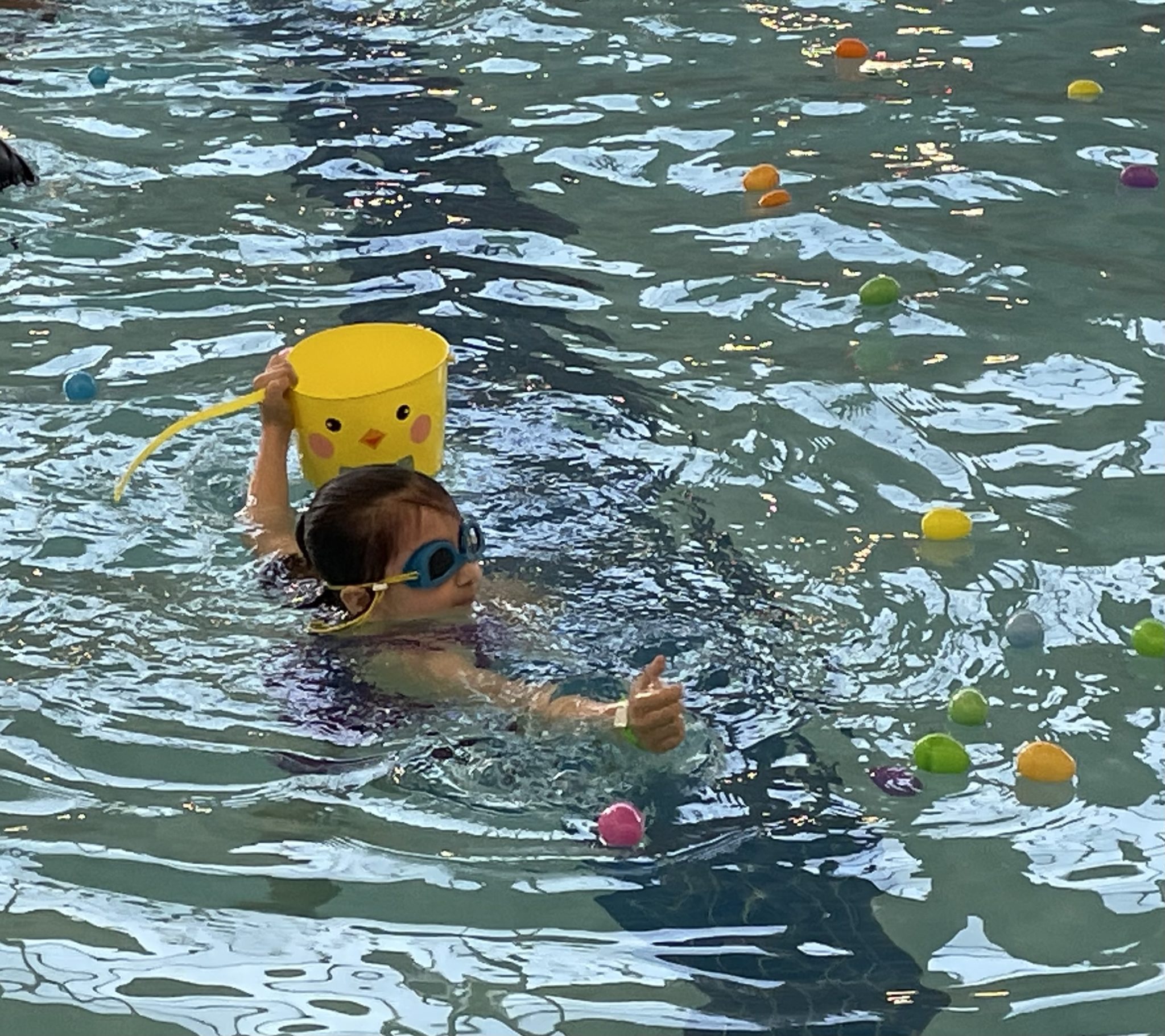 little girl races to catch Easter eggs in pool