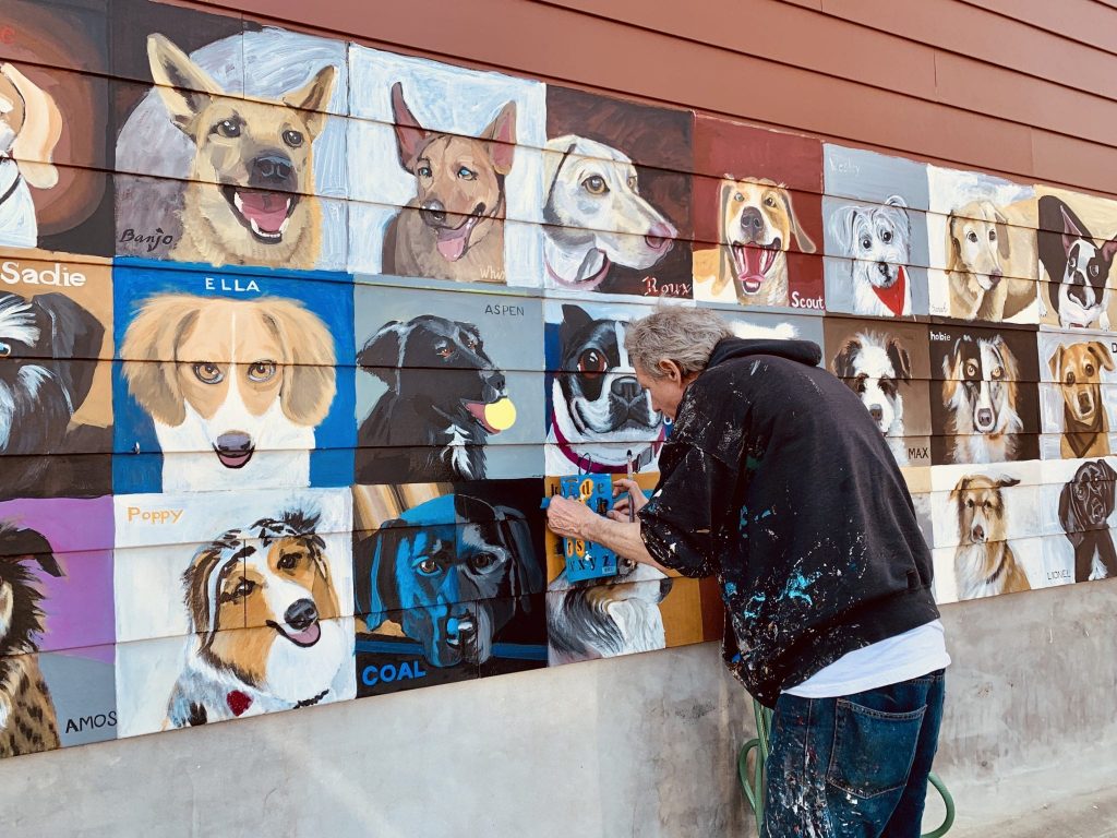 Artist Patrick Kirwin paints a dog on the famous Dogs of Del Ray mural.