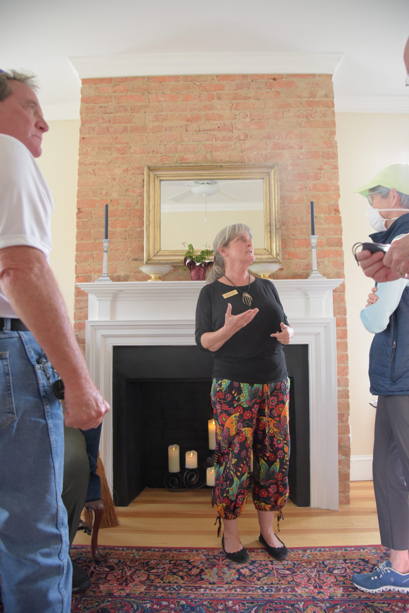 Woman standing in front of fireplace speaking to crowd.