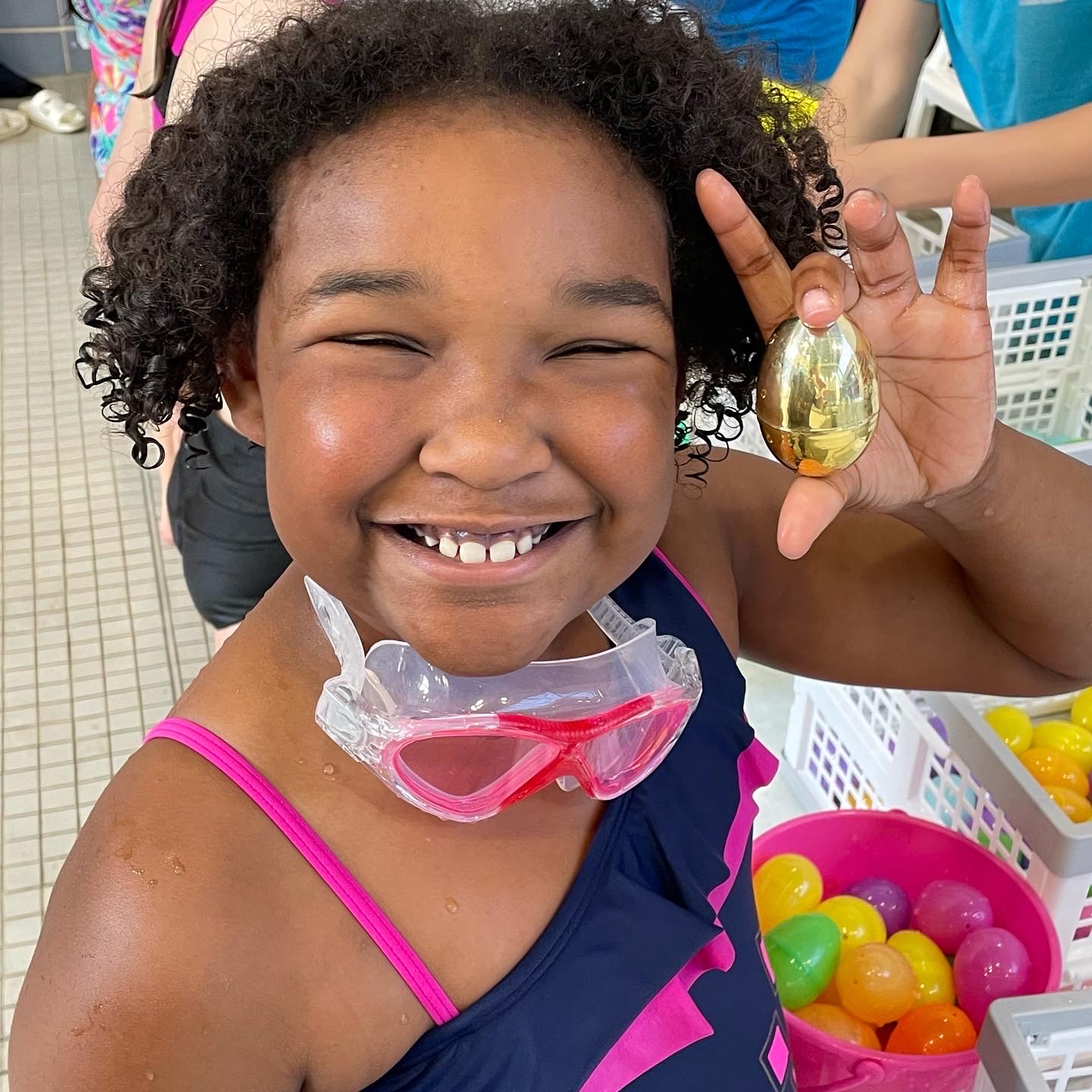 little girl smiling holding golden Easter egg in her hand