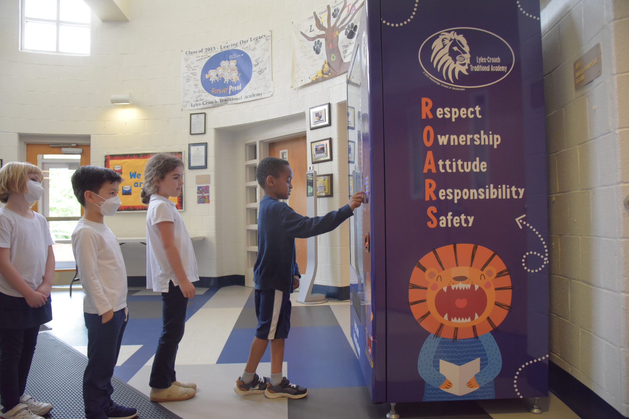 students wait in line at a book vending machine