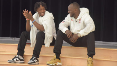 two men sit on stage and smile