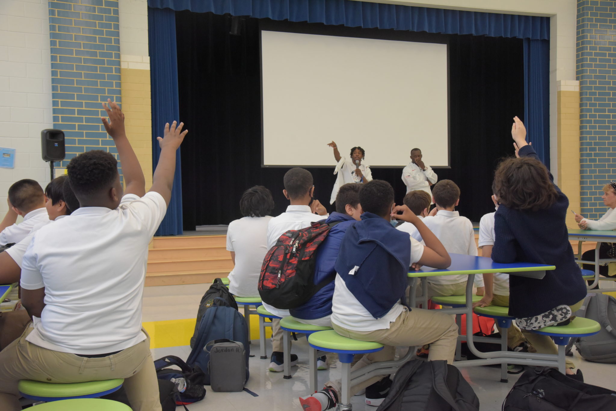 children raising their hands in cafeteria